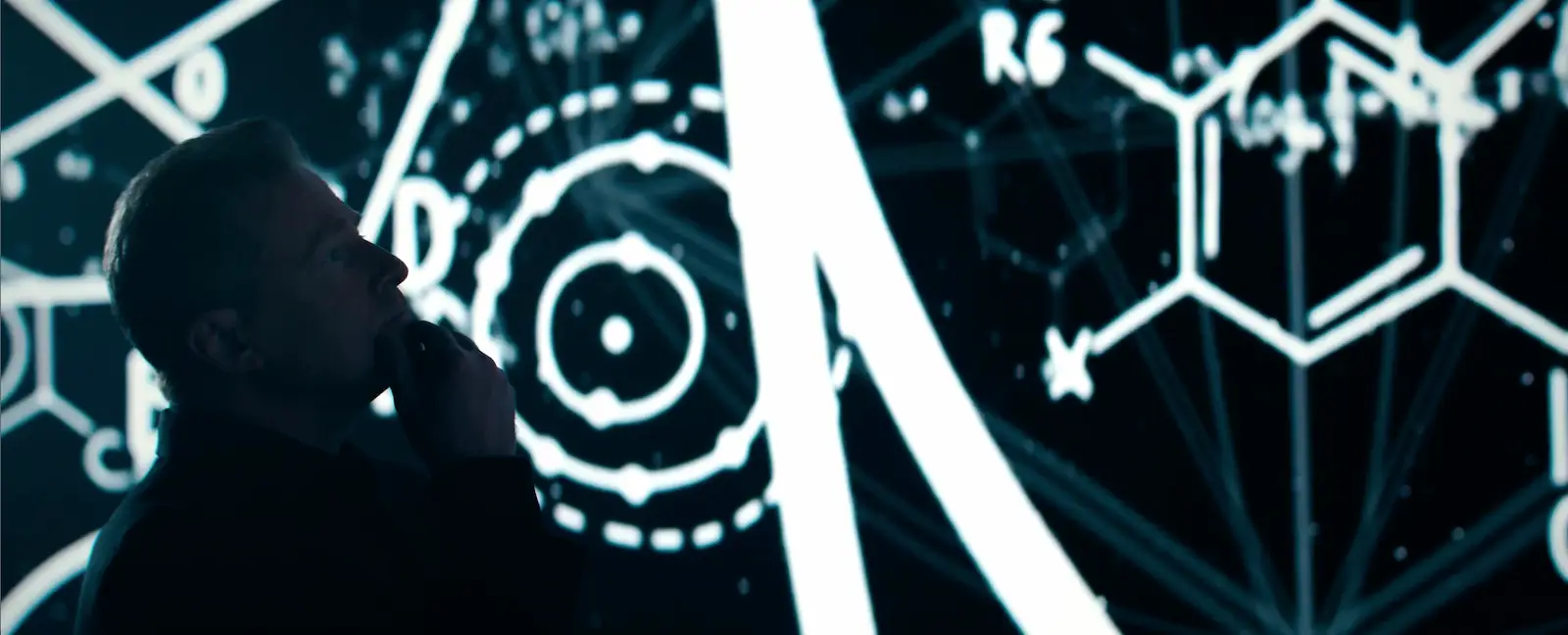 Silhouette of a David Schmidt contemplating with abstract scientific and geometric diagrams projected behind him